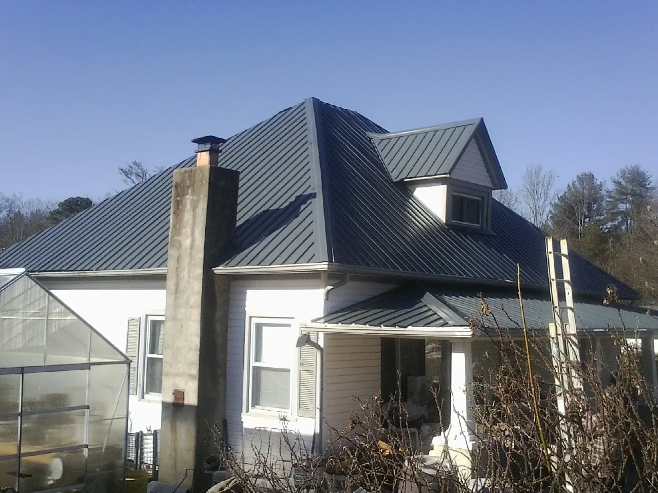 Dark blue standing seam metal roof on a white farmhouse with dormer — Slate & Tile Roof Repair by Roofing Brothers in Mount Ulla