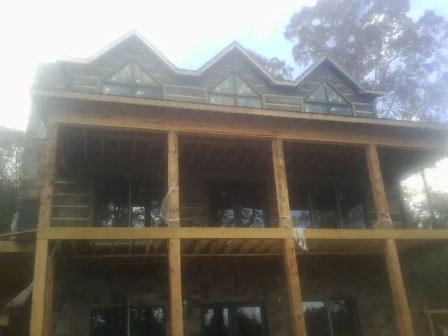 Dormers and porch framing on a large log home under construction — Roof Coating work by our crew in Mount Ulla