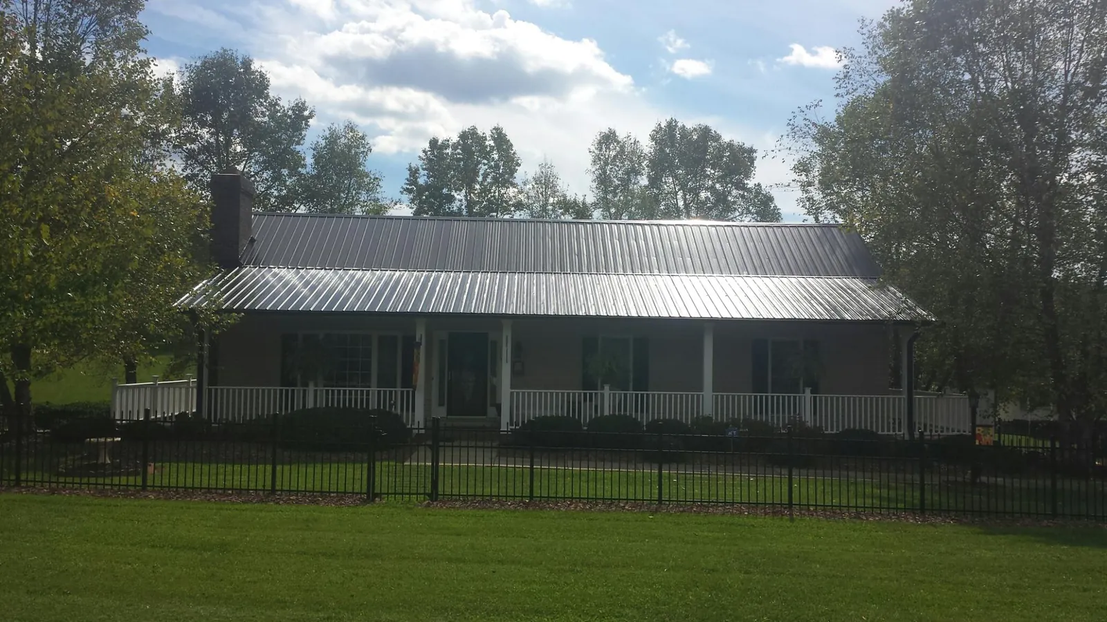 Gray metal roof on a brick ranch with a full width front porch — Gutter Guard Installation work by our crew in Mount Ulla