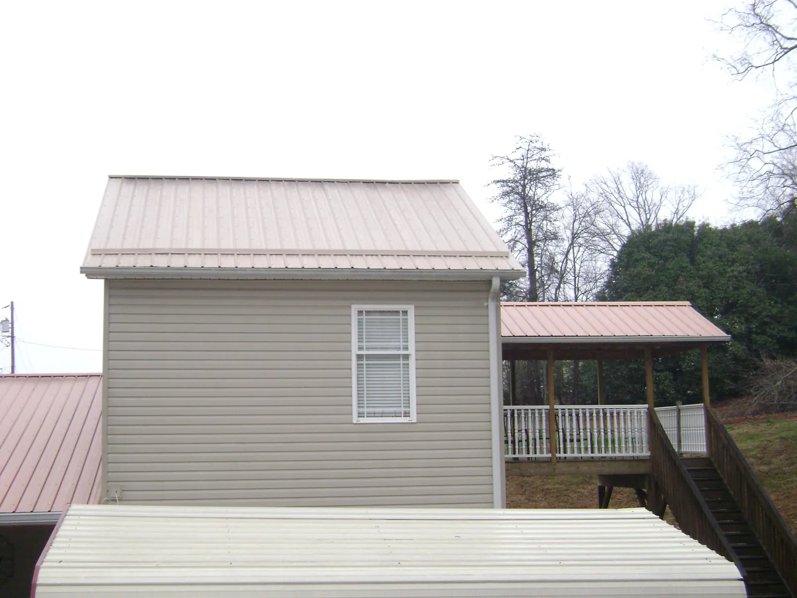 Tan metal roofs on a two story addition and attached porch, from a Roof Replacement job in Mount Ulla
