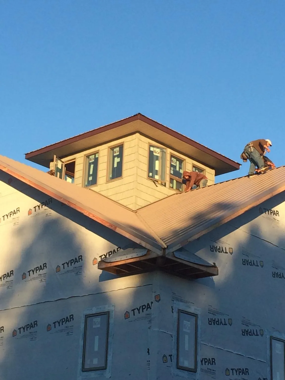 Roofers working around a rooftop cupola on a new metal roof at sunset — Roof Waterproofing in Mount Ulla by Roofing Brothers